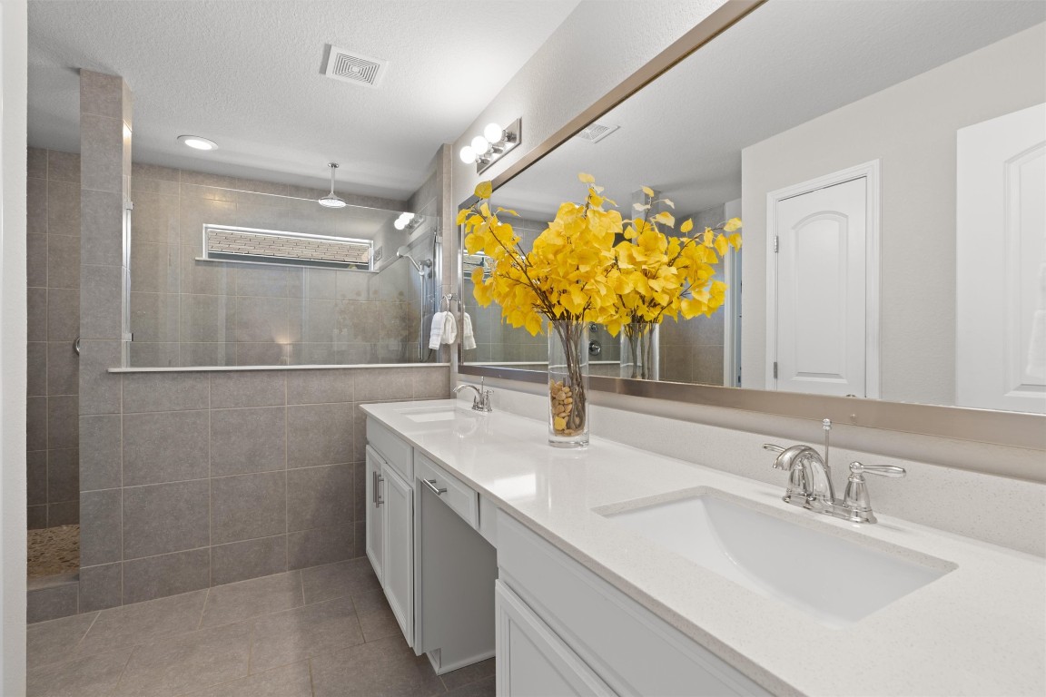 10502 Turnbull Loop, Unit 41 Austin, TX 78717 - Photo 16 of 29 Bathroom with double vanity, walk in shower, light tile patterned flooring, and a textured ceiling