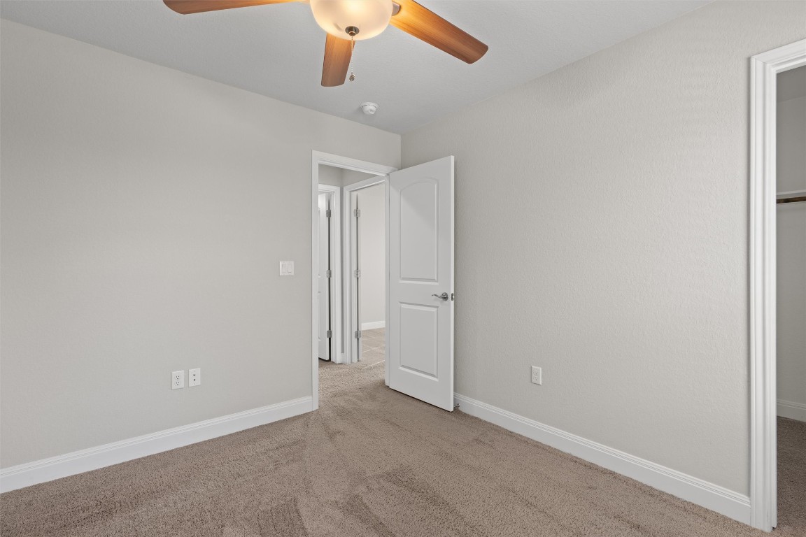 10502 Turnbull Loop, Unit 41 Austin, TX 78717 - Photo 20 of 29 Unfurnished bedroom with a walk in closet, carpet floors, and a ceiling fan