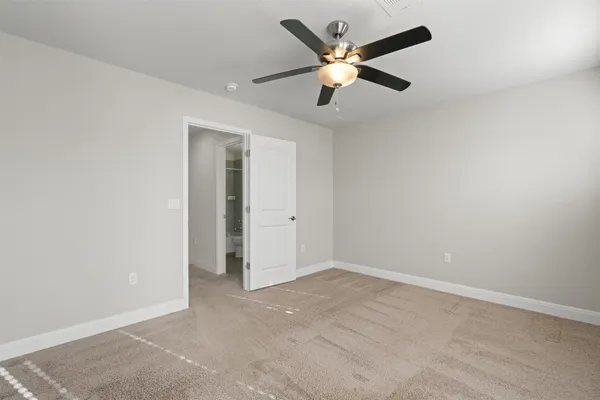 an empty room with chandelier fan and windows