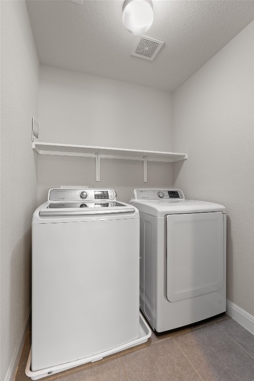 10502 Turnbull Loop, Unit 41 Austin, TX 78717 - Photo 24 of 29 Laundry room featuring washing machine and clothes dryer, light tile patterned floors, and a textured ceiling