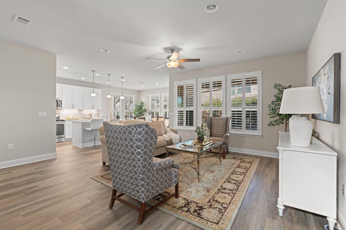 10502 Turnbull Loop, Unit 41 Austin, TX 78717 - Photo 4 of 29 Light-filled living room with expansive windows, elegant plantation shutters, LVP flooring, recessed lighting, and a ceiling fan.