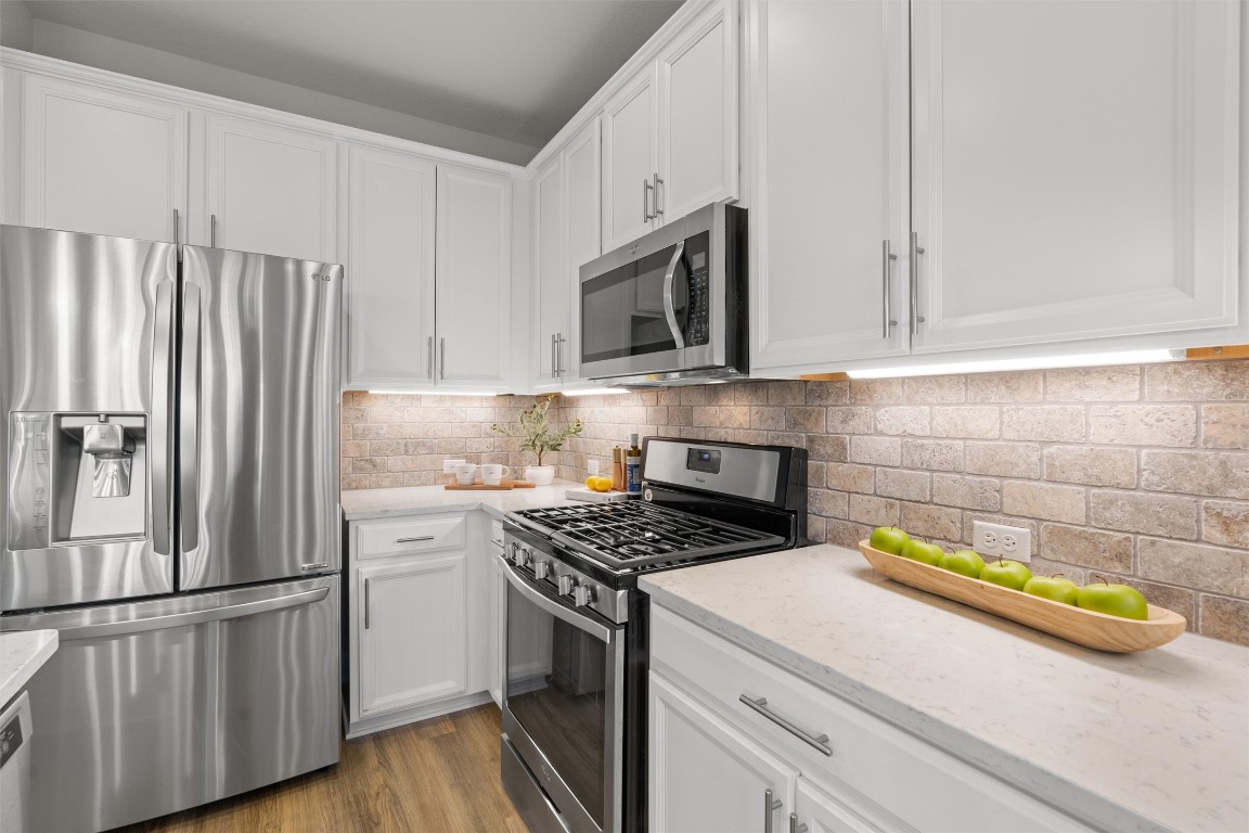 10502 Turnbull Loop, Unit 41 Austin, TX 78717 - Photo 9 of 29 Kitchen featuring stainless steel appliances, white cabinets, light stone countertops, and backsplash
