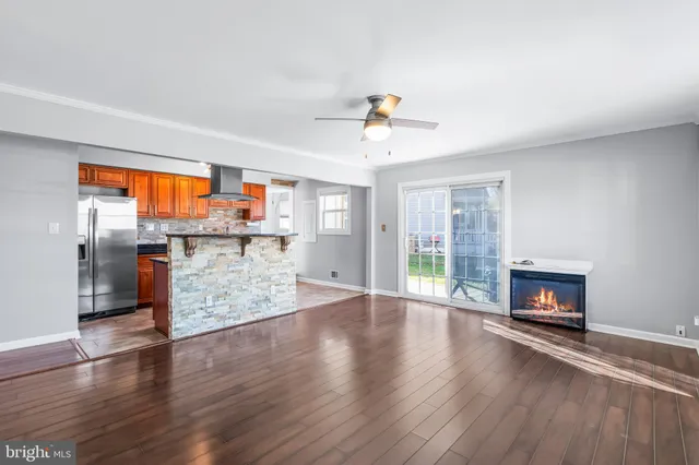 an empty room with wooden floor fireplace and windows