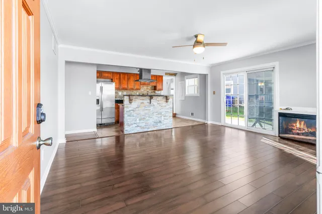 an empty room with wooden floor fireplace and windows