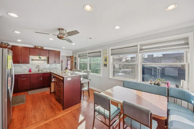 a open kitchen with stainless steel appliances granite countertop a refrigerator a sink dishwasher a stove and a dining table with wooden floor