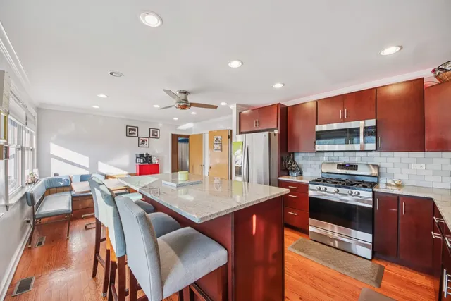 a kitchen with stainless steel appliances granite countertop a refrigerator a stove top oven a sink dishwasher and white cabinets with wooden floor