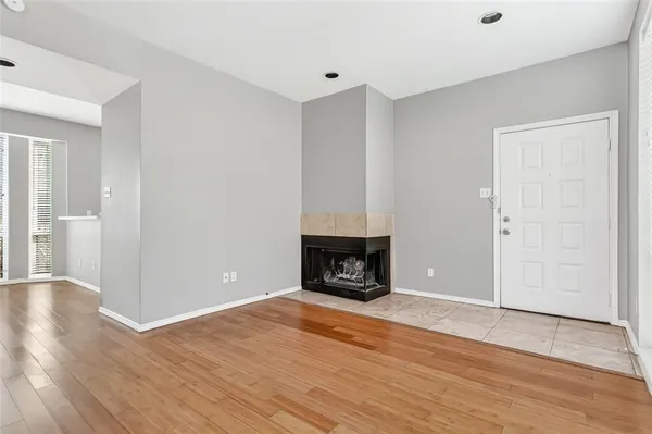 an empty room with wooden floor fireplace and windows