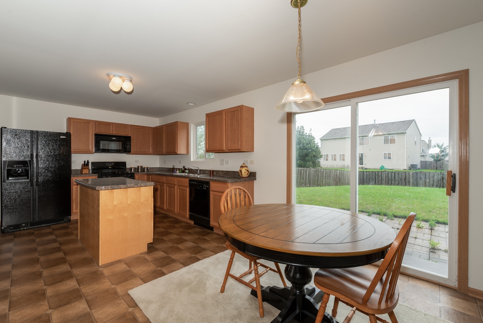 1143 Port Royal Road Pingree Grove, IL 60140 - Photo 4 of 13 a kitchen with a table chairs refrigerator and microwave