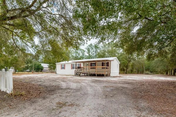 a view of a house with a yard and large trees
