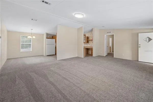 a view of empty room with windows and refrigerator