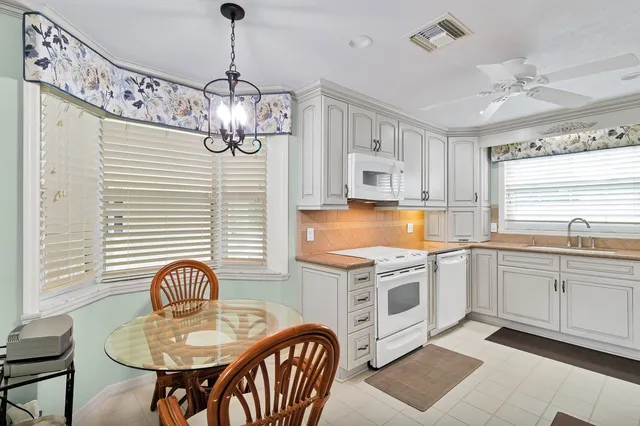 a kitchen with stainless steel appliances granite countertop a kitchen island a stove a sink a dining table and chairs with wooden floor