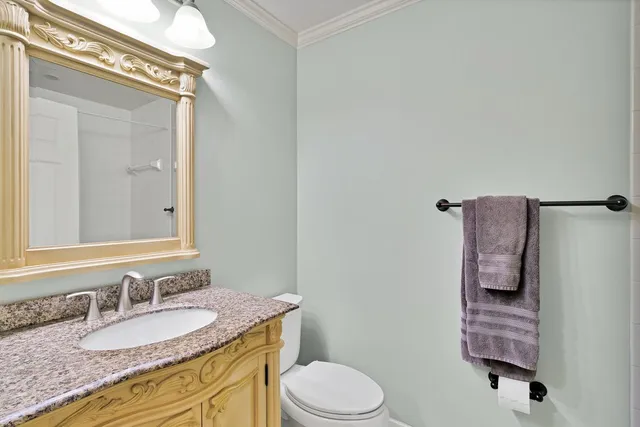 a bathroom with a granite countertop sink vanity mirror and toilet
