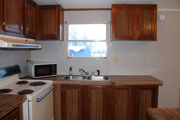 a kitchen with a sink a stove cabinets and a window