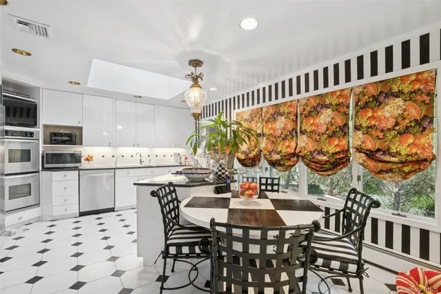 a kitchen with stainless steel appliances kitchen island granite countertop a dining table chairs and a sink