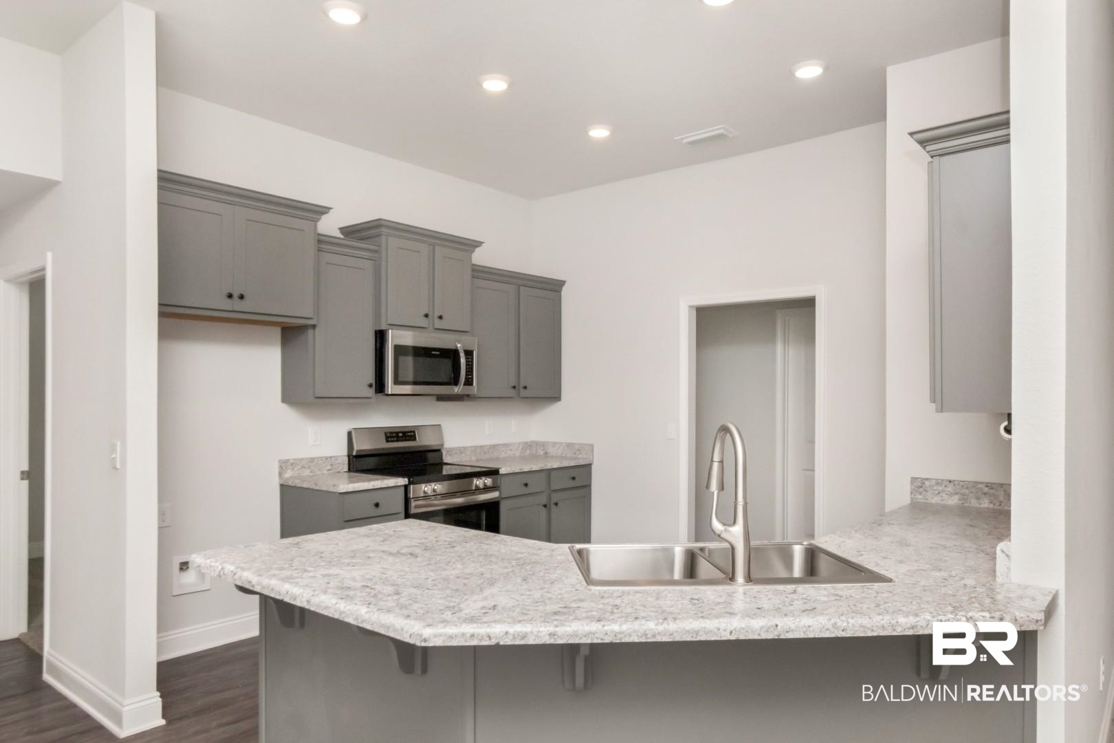 6632 Monarch Circle Mobile, AL 36618 - Photo 11 of 32 Kitchen with a kitchen breakfast bar, gray cabinets, stainless steel appliances, a peninsula, and dark wood-style floors
