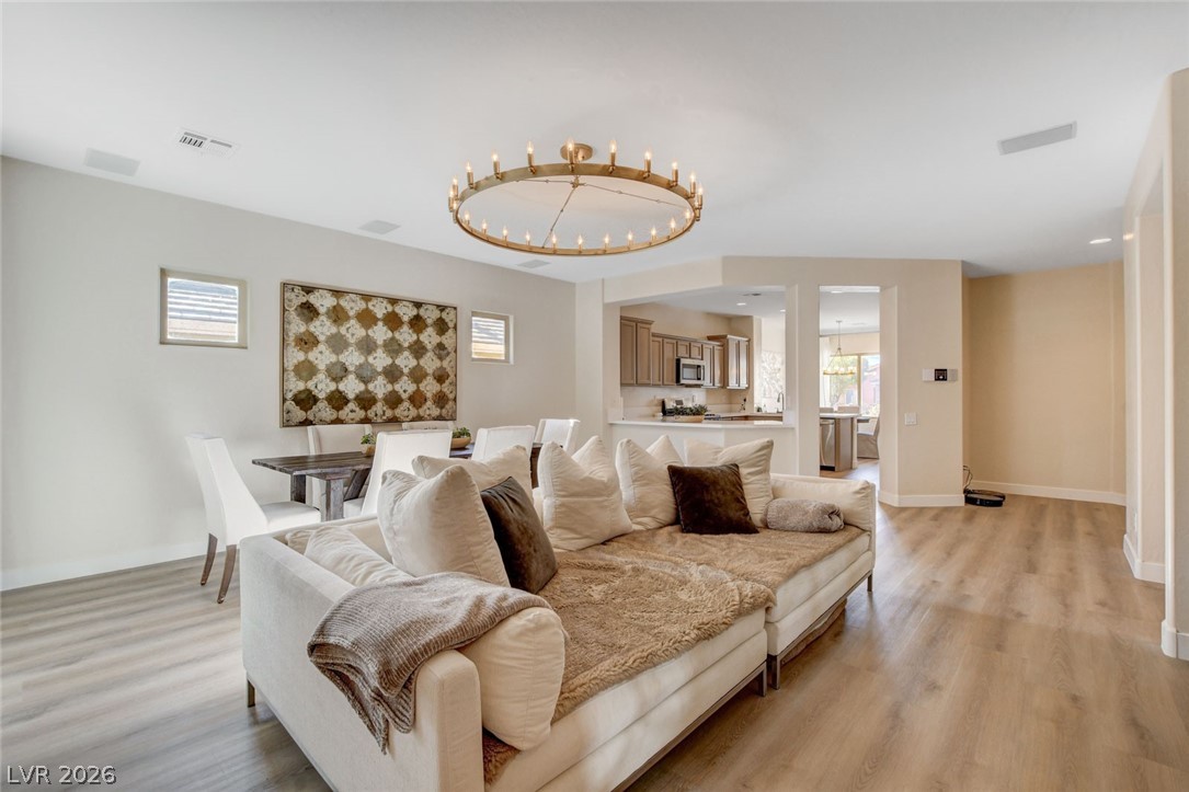 2649 Rue Marquette Avenue Henderson, NV 89044 - Photo 14 of 55 An inviting open-concept living space showcases light wood-style flooring and a distinctive circular chandelier.
