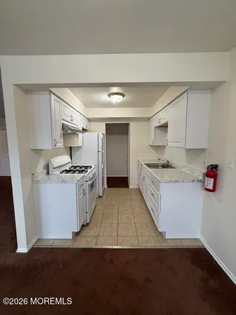 a kitchen with a refrigerator and white cabinets