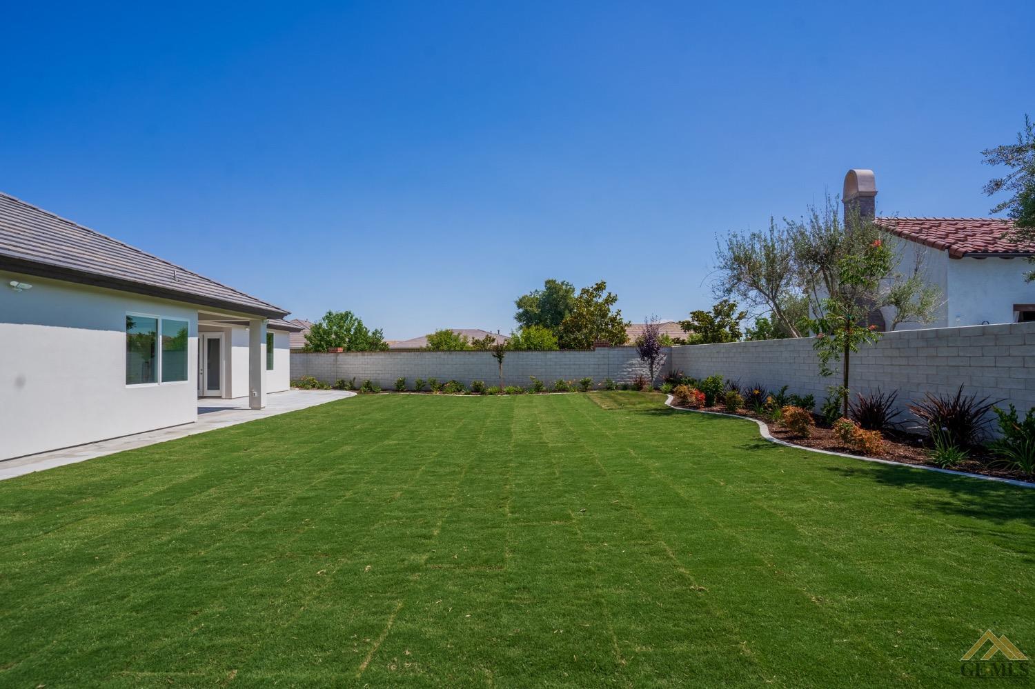 Undisclosed Address Bakersfield, CA 93311 - Photo 67 of 75 a backyard of a house with table and chairs plants and large tree