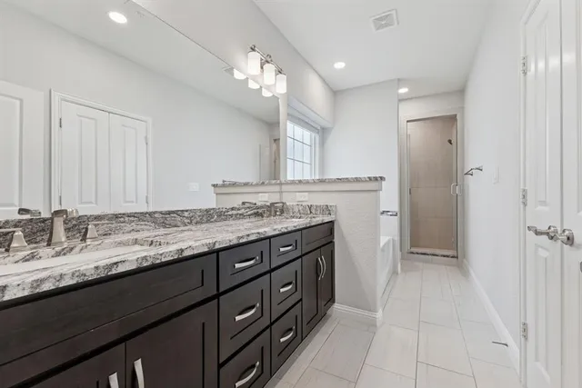 a bathroom with a granite countertop double vanity sink and a mirror