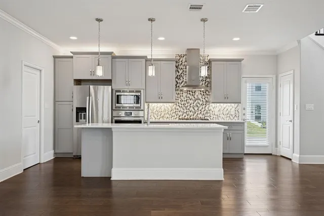 a kitchen with stainless steel appliances granite countertop a refrigerator a oven and a wooden floors