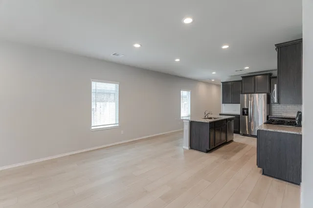 a view of kitchen with stainless steel appliances granite countertop a stove top oven a sink a refrigerator and dishwasher with wooden floor