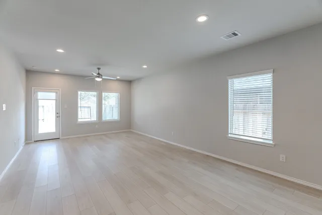an empty room with wooden floor and windows