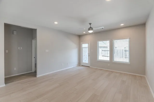 a view of an empty room with a window and wooden floor