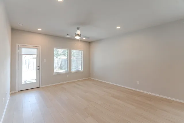 an empty room with a window and a fan