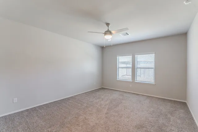 en empty room with ceiling fan and window
