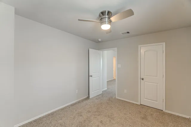 an empty room with windows and ceiling fan
