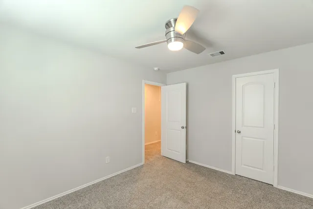 an empty room with a window and ceiling fan