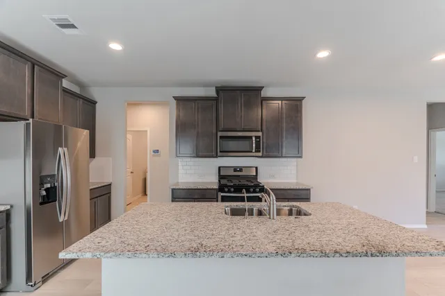 a kitchen with stainless steel appliances granite countertop a sink refrigerator and stove
