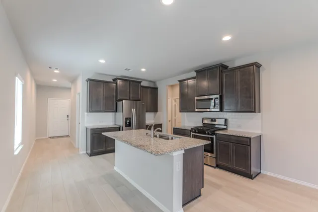a kitchen with stainless steel appliances granite countertop a sink stove and refrigerator