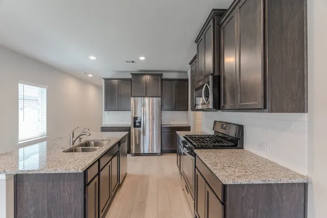 a kitchen with granite countertop stainless steel appliances a sink stove and refrigerator