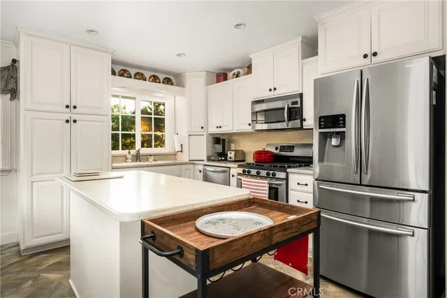 a kitchen with kitchen island a counter appliances a sink and a window