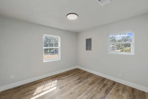 a view of empty room with wooden floor and fan