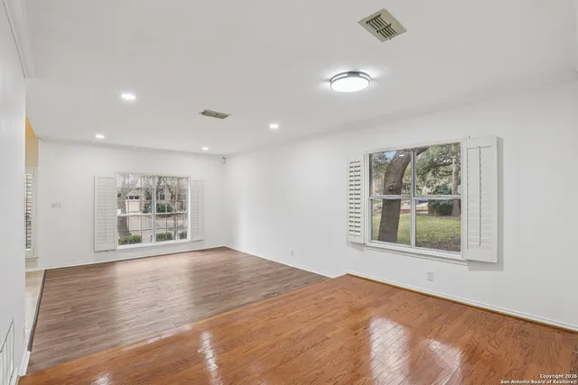 a view of an empty room with a window and wooden floor