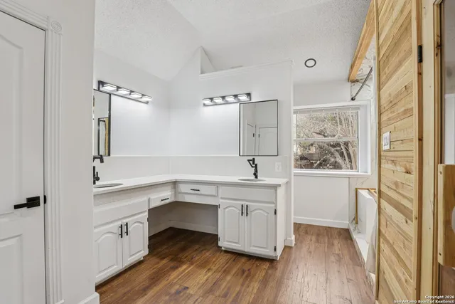 a view of cabinets a sink wooden floor and a window