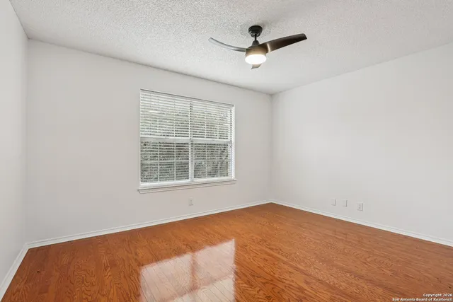 an empty room with a window and a ceiling fan