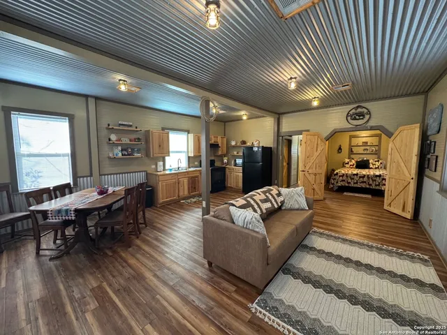 a living room with furniture a table wooden floor and a large window