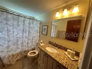 a bathroom with a granite countertop sink toilet and a mirror