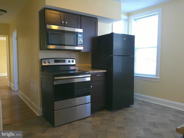 a kitchen with granite countertop a refrigerator and a stove top oven