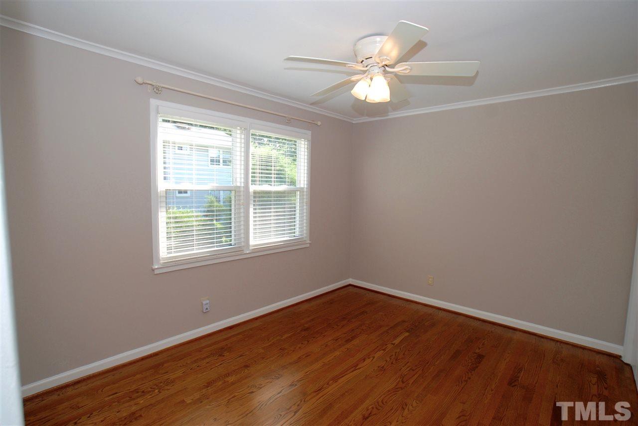 803 Daniels Street, Unit B Raleigh, NC 27605 - Photo 6 of 22 an empty room with wooden floor chandelier fan and windows
