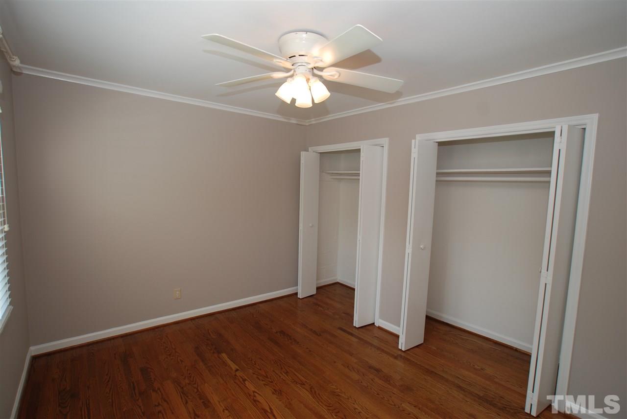 803 Daniels Street, Unit B Raleigh, NC 27605 - Photo 8 of 22 an empty room with wooden floor chandelier fan and windows