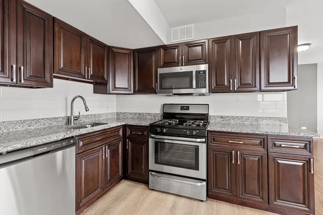 a kitchen with granite countertop wooden cabinets and stainless steel appliances