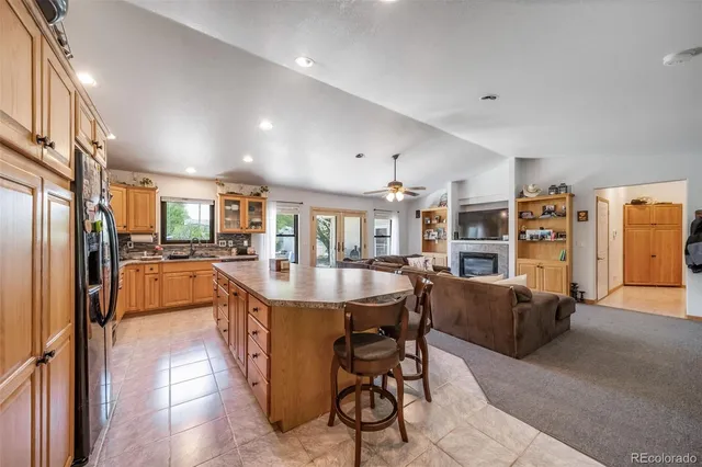 a dining hall with stainless steel appliances kitchen island granite countertop a refrigerator a stove a sink dishwasher and a dining table with the kitchen view
