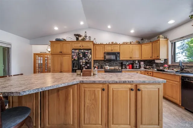 a kitchen with stainless steel appliances kitchen island granite countertop a table chairs sink and cabinets