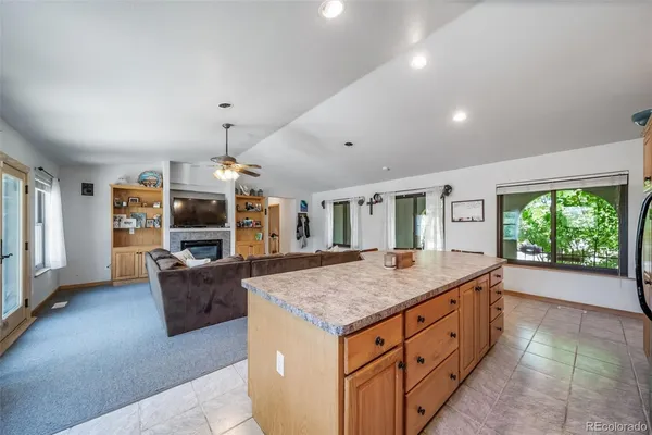 a view of living room kitchen with stainless steel appliances granite countertop cabinets and fireplace