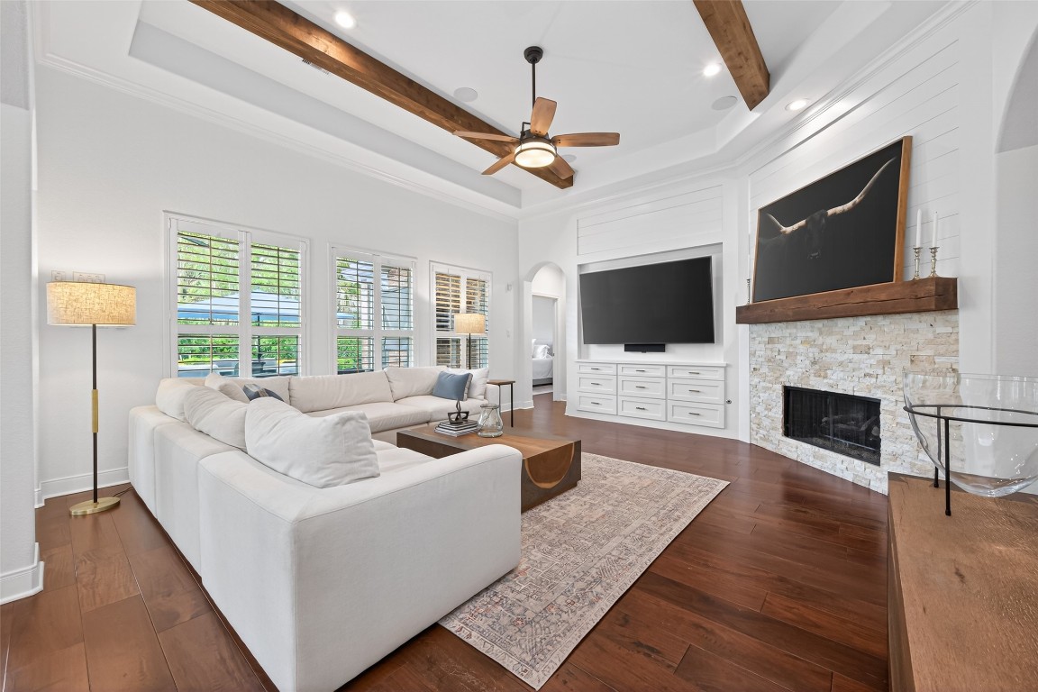 18207 Yukon Ridge Trail Humble, TX 77346 - Photo 14 of 49 This inviting living room features a modern fireplace. The space is enhanced by natural light through plantation shutters, wooden ceiling beams, and a custom built entertainment center.