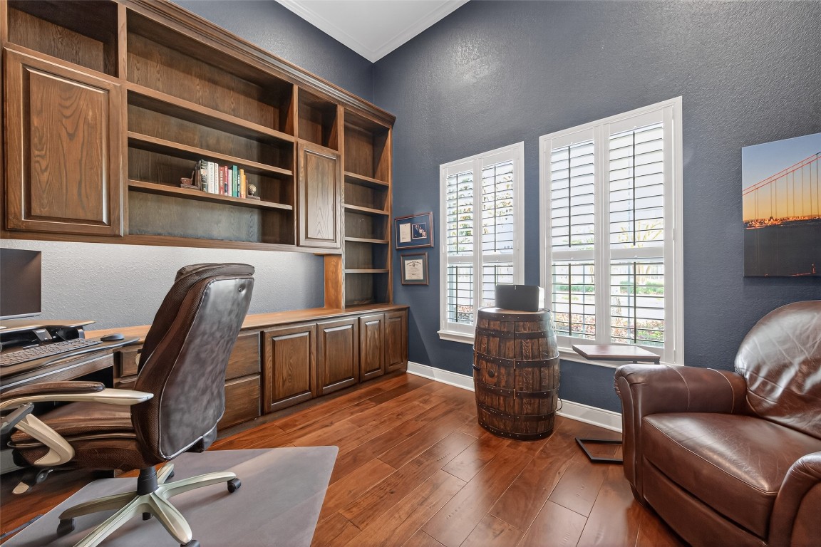 18207 Yukon Ridge Trail Humble, TX 77346 - Photo 6 of 49 This home office features rich wooden built-in shelves and cabinets, sleek hardwood floors, and ample natural light from large windows.
